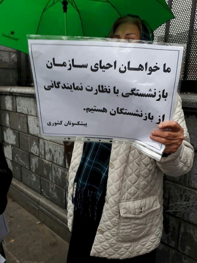A woman holds a sign showing, “We demand the restoration of the Retirees Organization under the supervision of a representative from the retirees’ community.” A woman holds a sign showing, “We demand the restoration of the Retirees Organization under the supervision of a representative from the retirees’ community.”