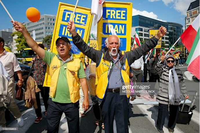 Iranians holding Iran’s national flag and posters while participating in organized march for a Free Iran